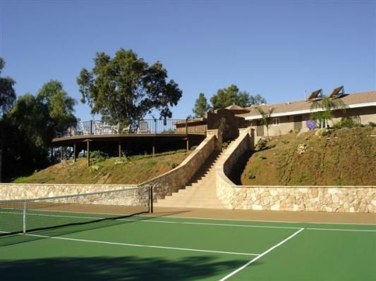 A tennis court with a house in the background
