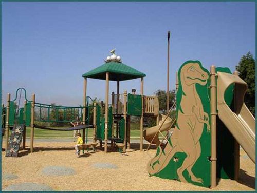 A child is playing in a playground with a dinosaur on it
