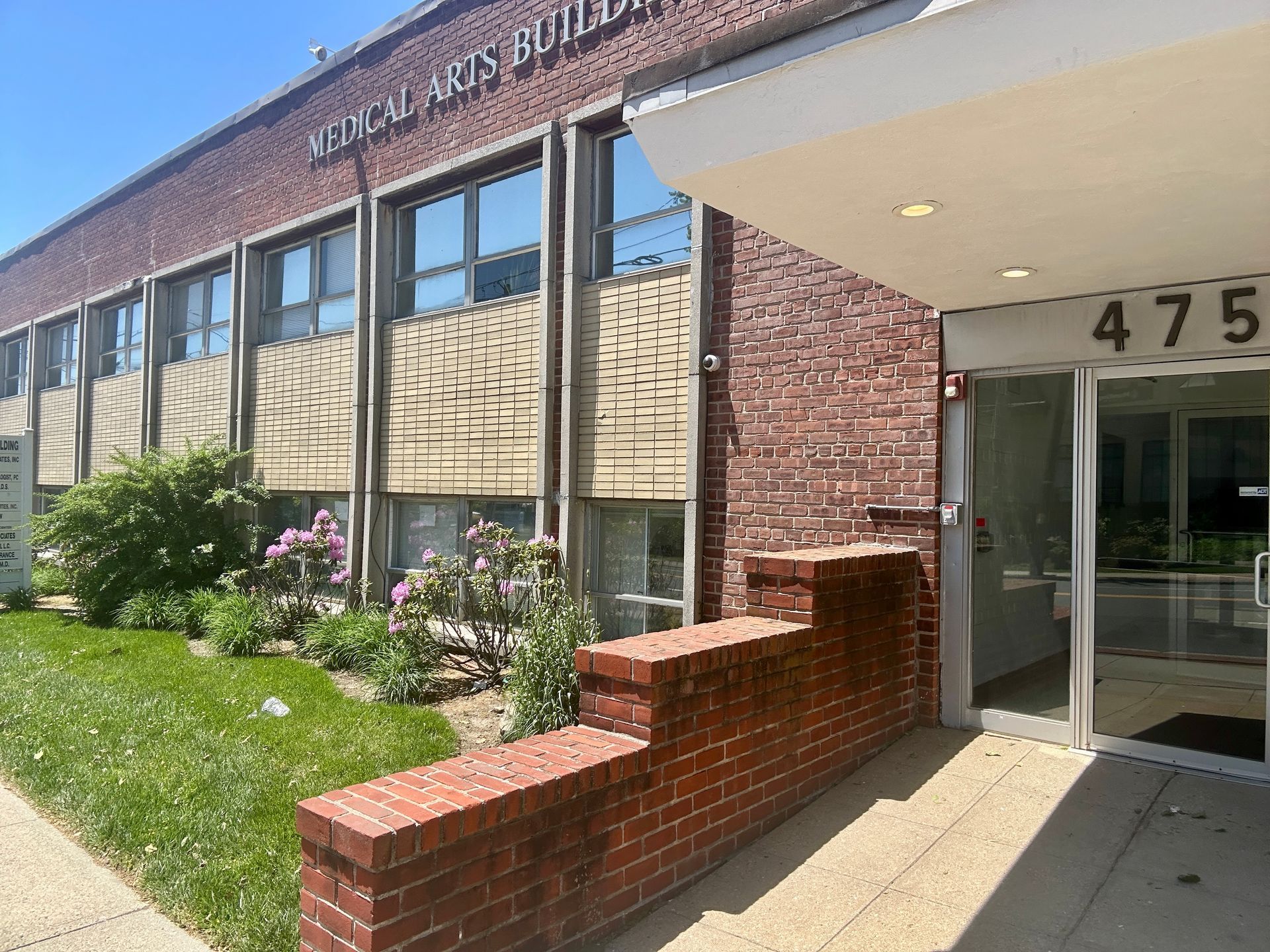 Office building entrance with brick facade, glass doors, and the number 475 above the doorway