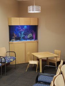A waiting room with a table and chairs and an aquarium.