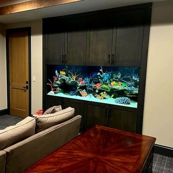 A living room with a couch , table and aquarium.