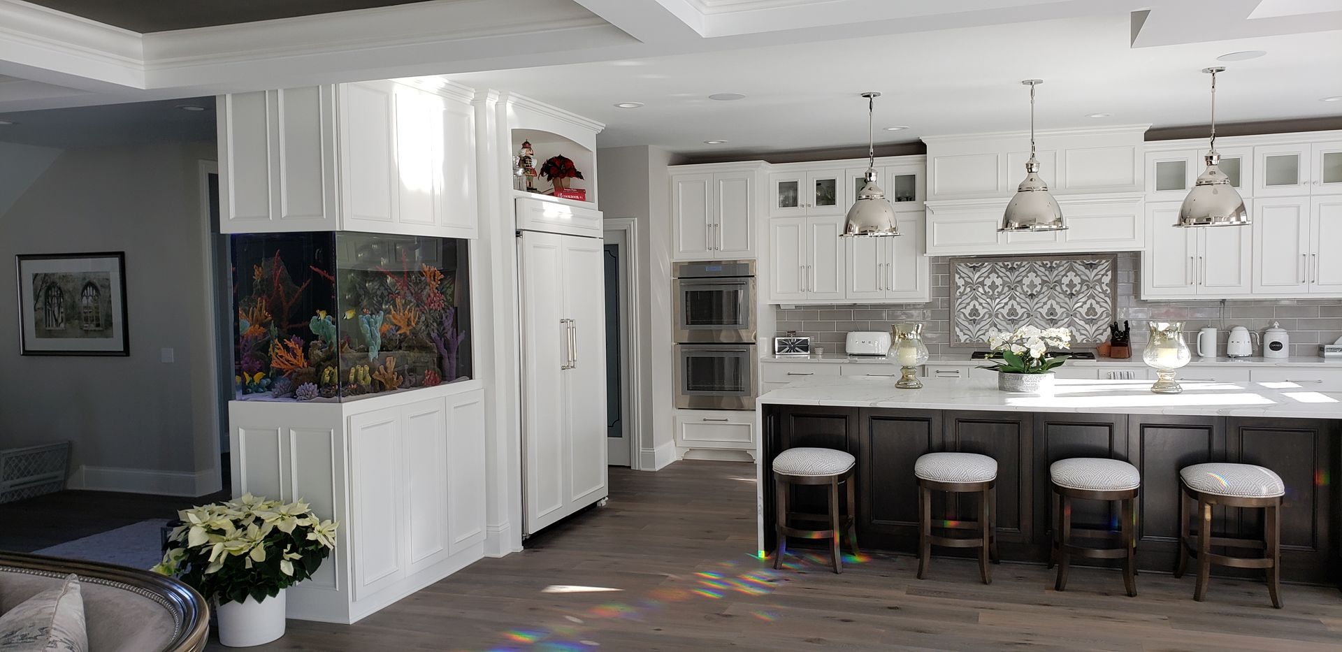 A kitchen with white cabinets and a large aquarium in the middle.