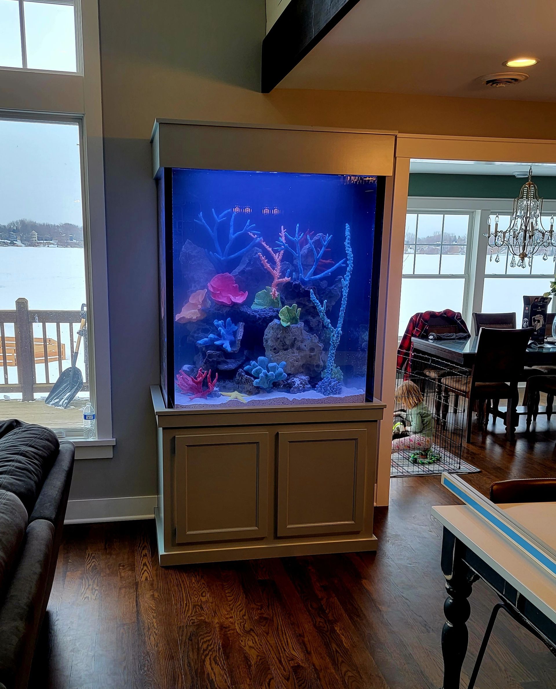 A large aquarium in a living room next to a pool table