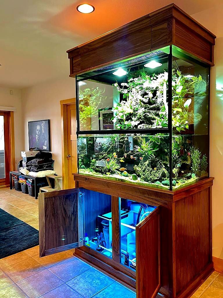 A large aquarium is sitting in a living room with its doors open.