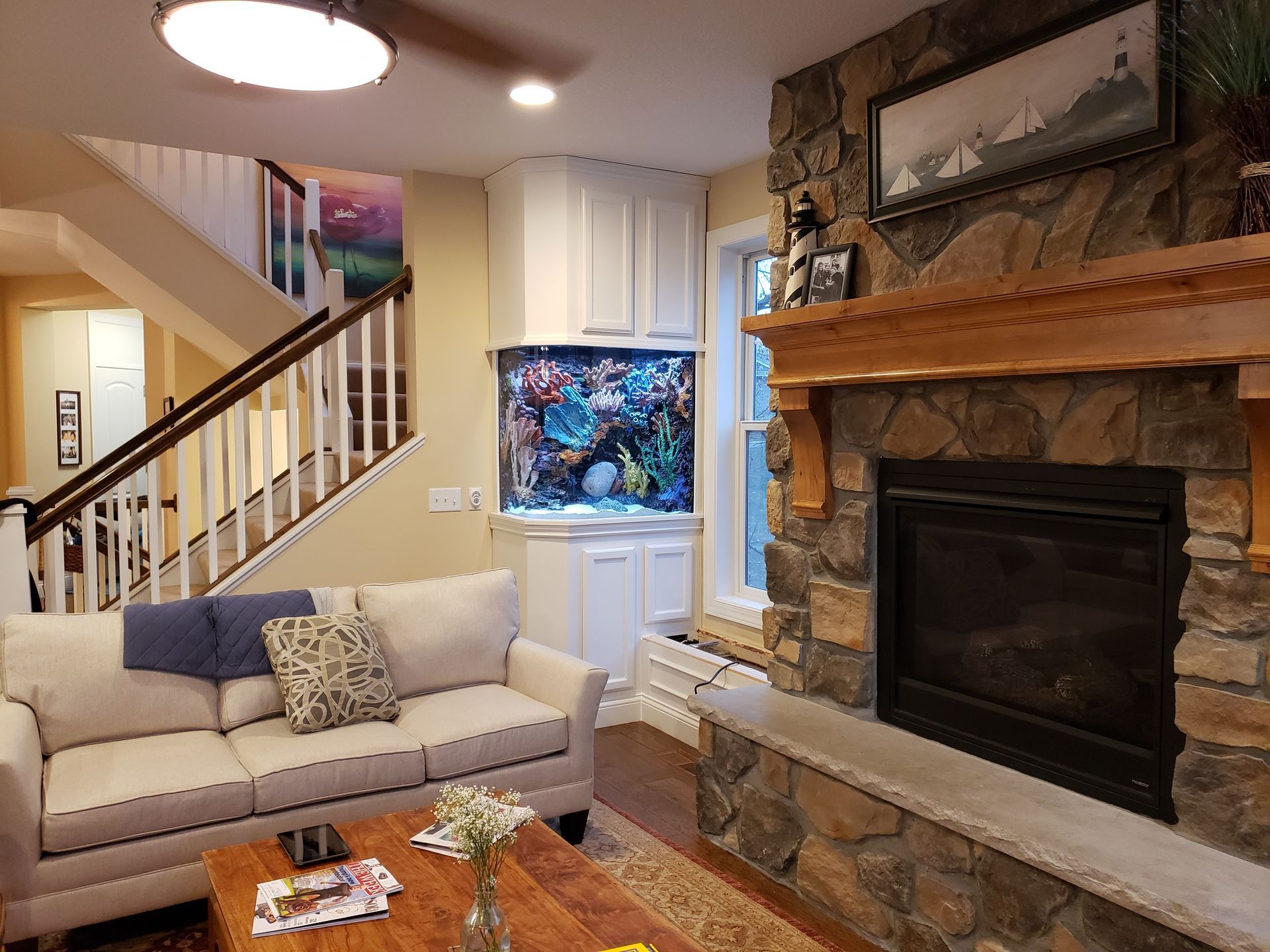 A living room with a couch , fireplace , and aquarium.