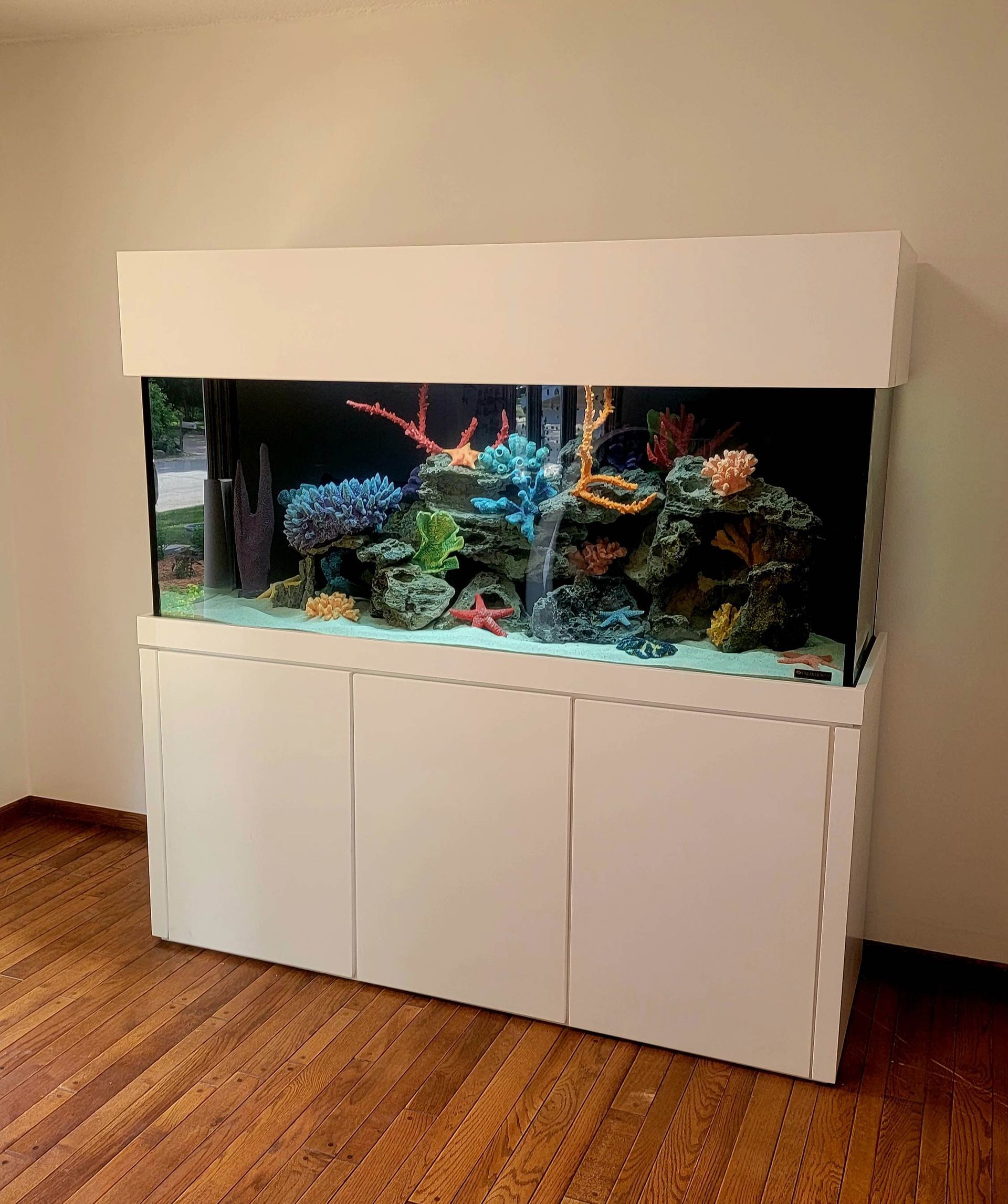 A large aquarium is sitting on top of a wooden floor in a room.