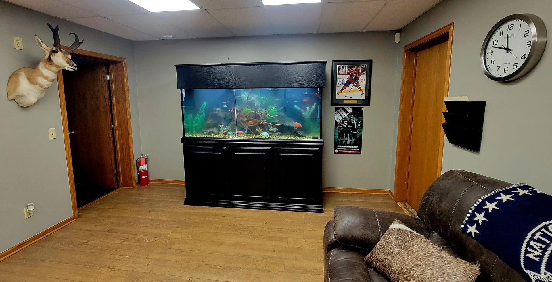 A living room with a couch , clock , and fish tank.