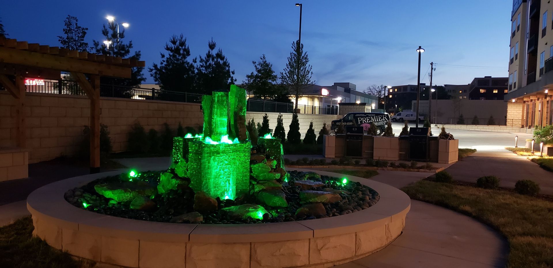 A fountain is lit up with green lights at night