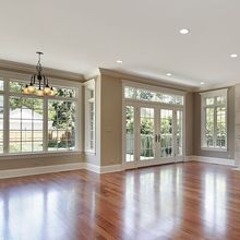 An empty living room with hardwood floors and lots of windows.