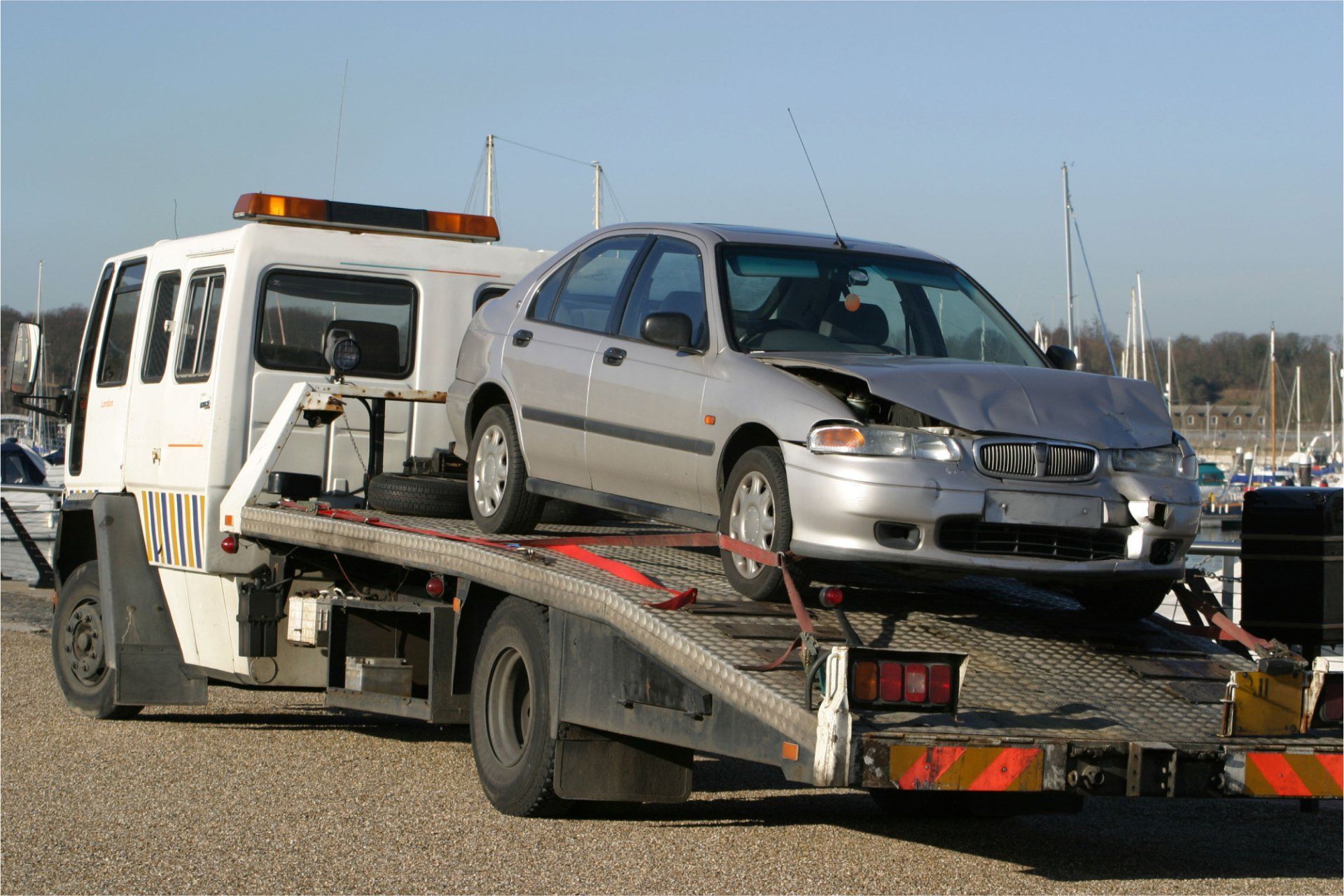 A silver car is being towed by a tow truck.