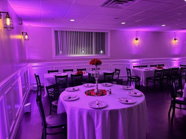 a room with tables and chairs and purple lights on the walls .