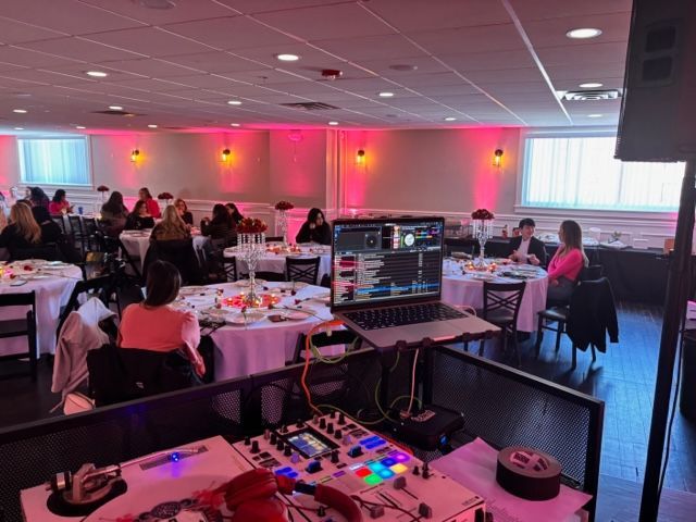 a dj is playing music in a large room with people sitting at tables .