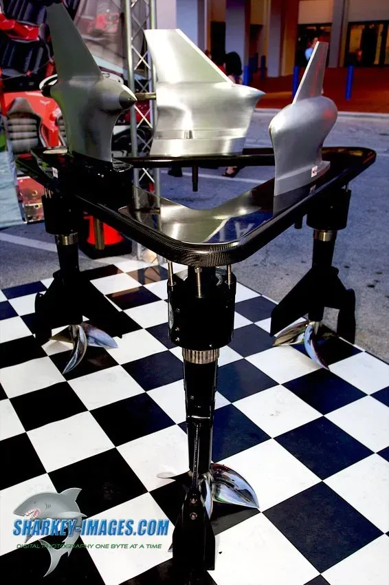 Three boat propellers displayed on a stand with a checkered floor.