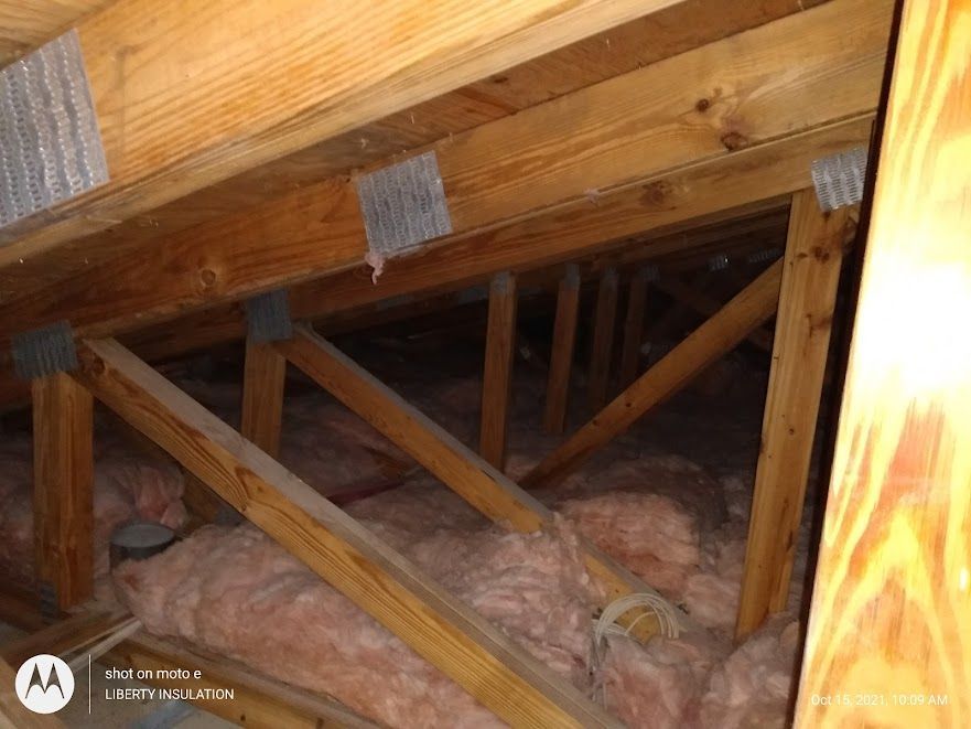 The ceiling of a house with wooden beams and insulation.