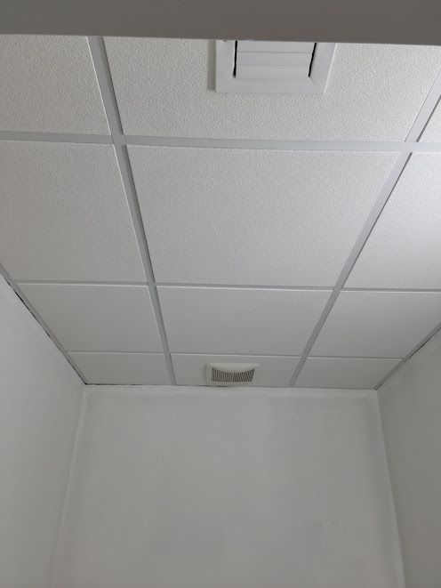A room with a tiled ceiling and white walls.