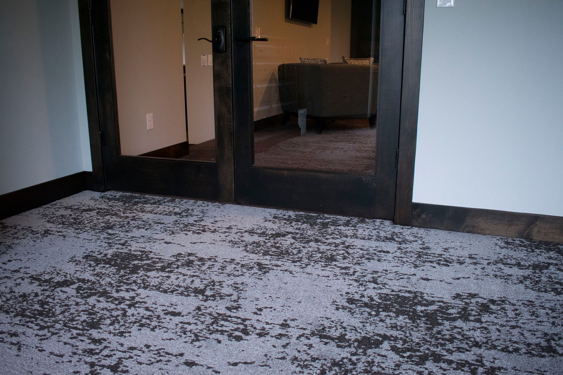 Empty hallway with double glass doors and a patterned carpeted floor