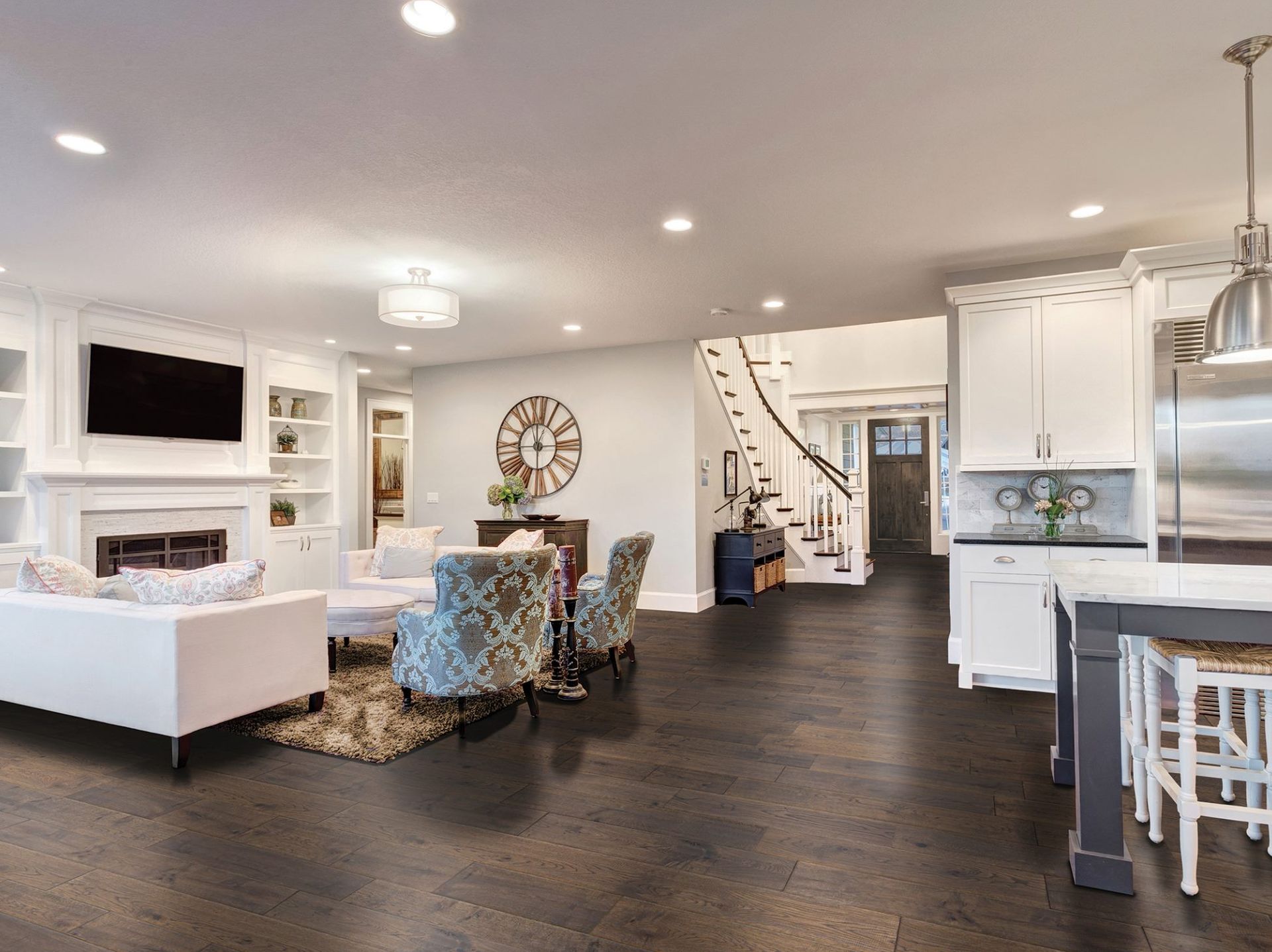 Bright open-plan living room with white sofa, fireplace, dining area, and dark wood floors