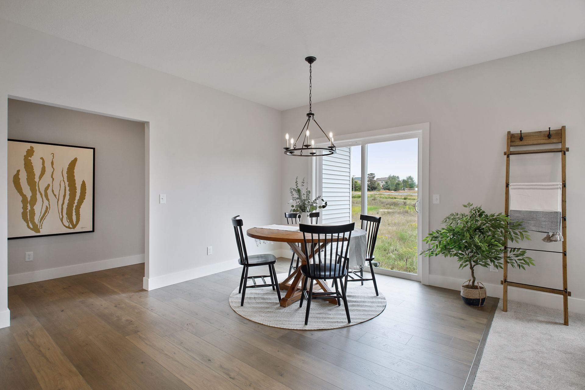 Bright dining area with round table, black chairs, pendant light, and sliding doors to a patio.