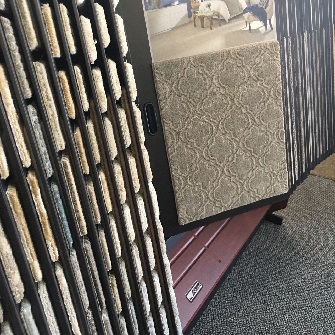 Brindle dog in a black crate, seen through the bars on a carpeted floor.