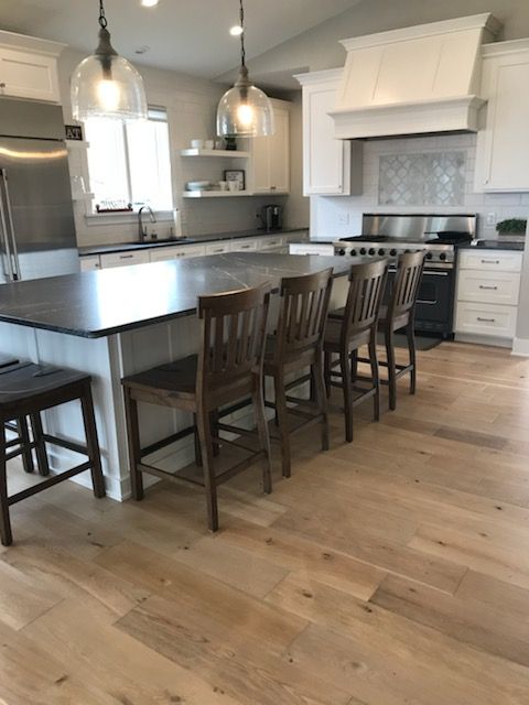 Bright modern kitchen with large island, bar stools, pendant lights, and hardwood floors