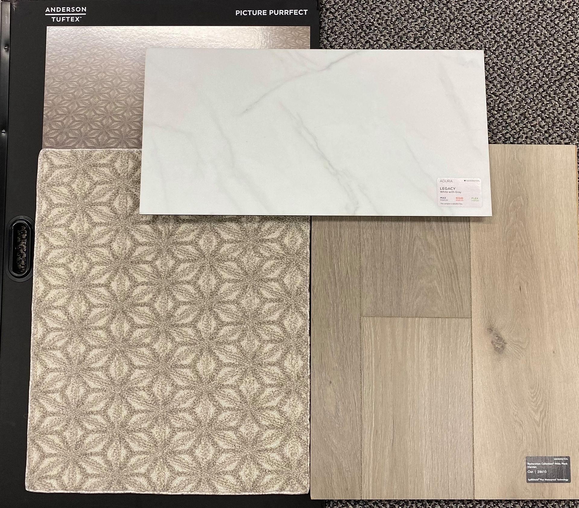 Sample flooring and wall covering materials laid out on a dark background.