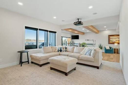 Bright living room with beige sectional, fireplace, wood beams, and large windows overlooking mountains