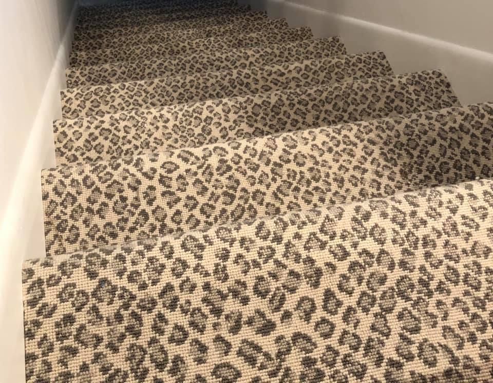 Leopard-print carpeted staircase with white walls and wooden trim