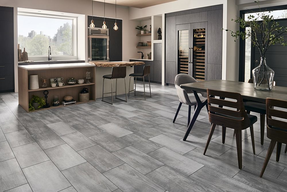 Modern kitchen and dining area with gray tile floor, wood island, pendant lights, and large windows