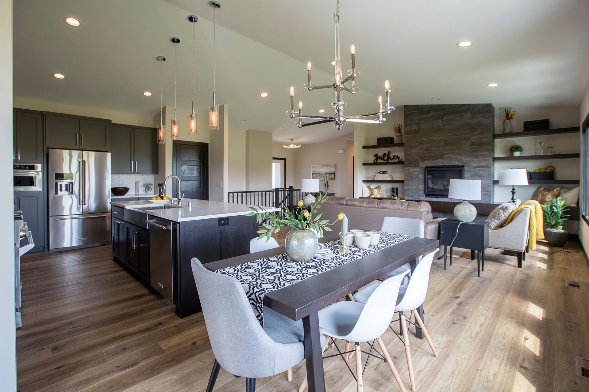 Open-plan kitchen and dining room with modern decor, wood floors, island, and fireplace