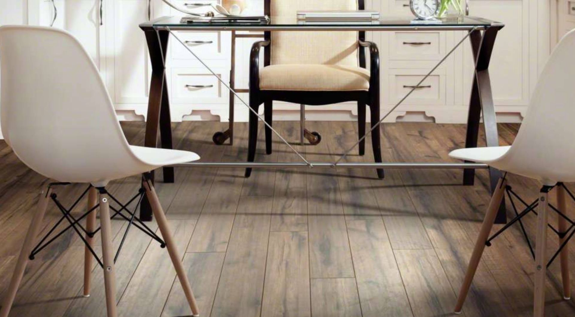Modern dining area with white chairs, a table, and a rustic wooden floor under natural light