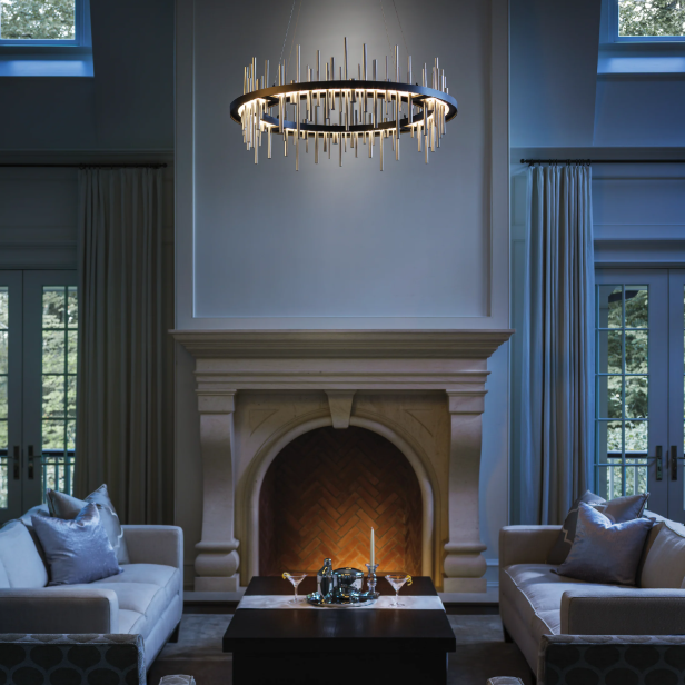 A symmetrical living room featuring two beige sofas, a stone fireplace, and a circular, icicle-style chandelier.