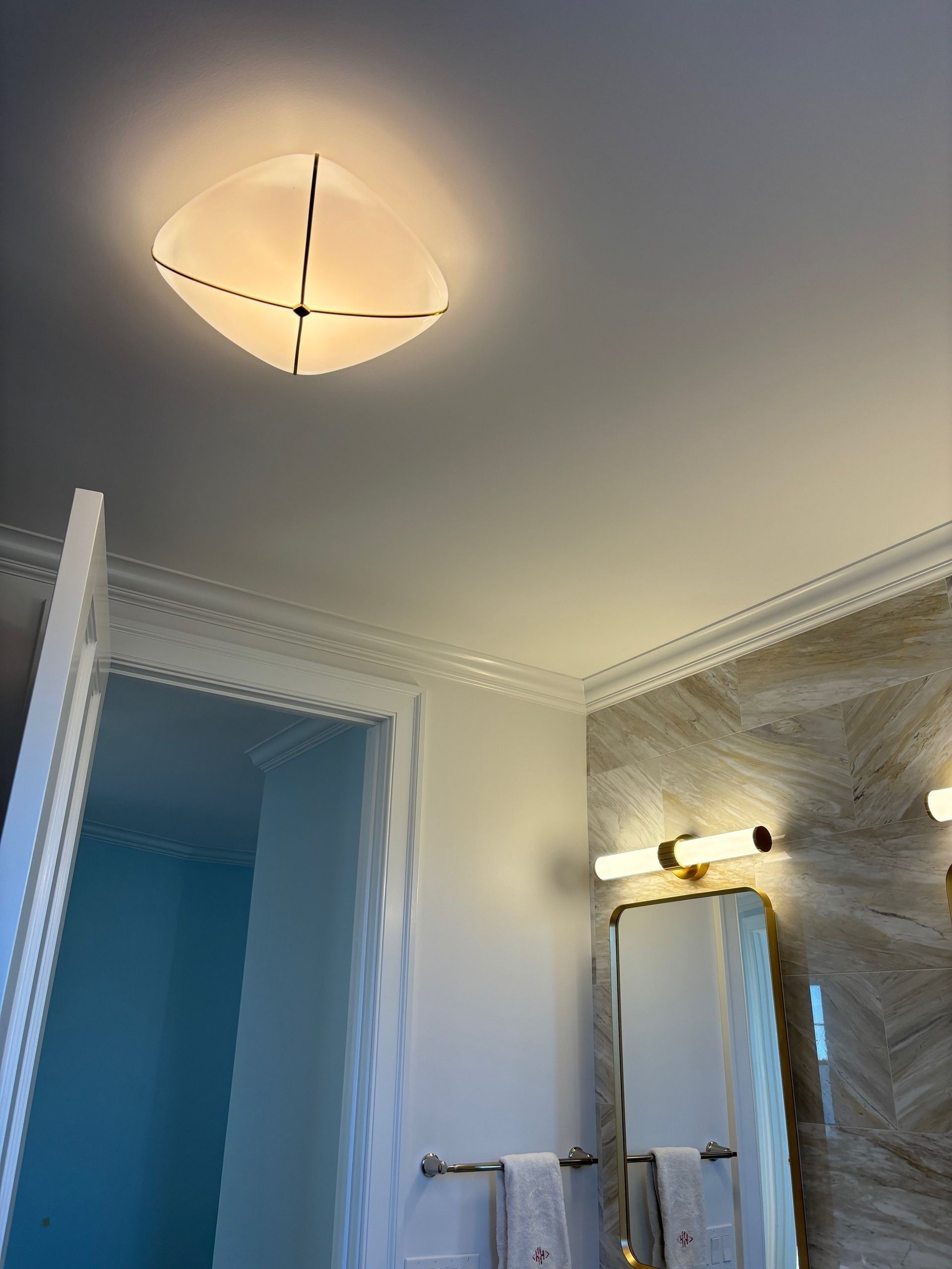 Bathroom interior with a ceiling light fixture, crown molding, and a wall-mounted mirror.