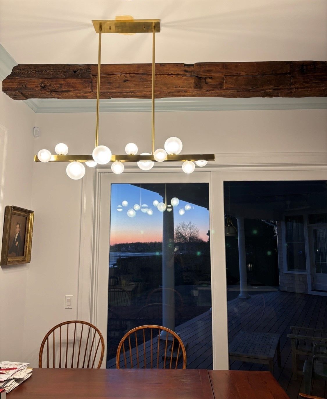 Dining room with a chandelier above a table, looking out onto the sunset.