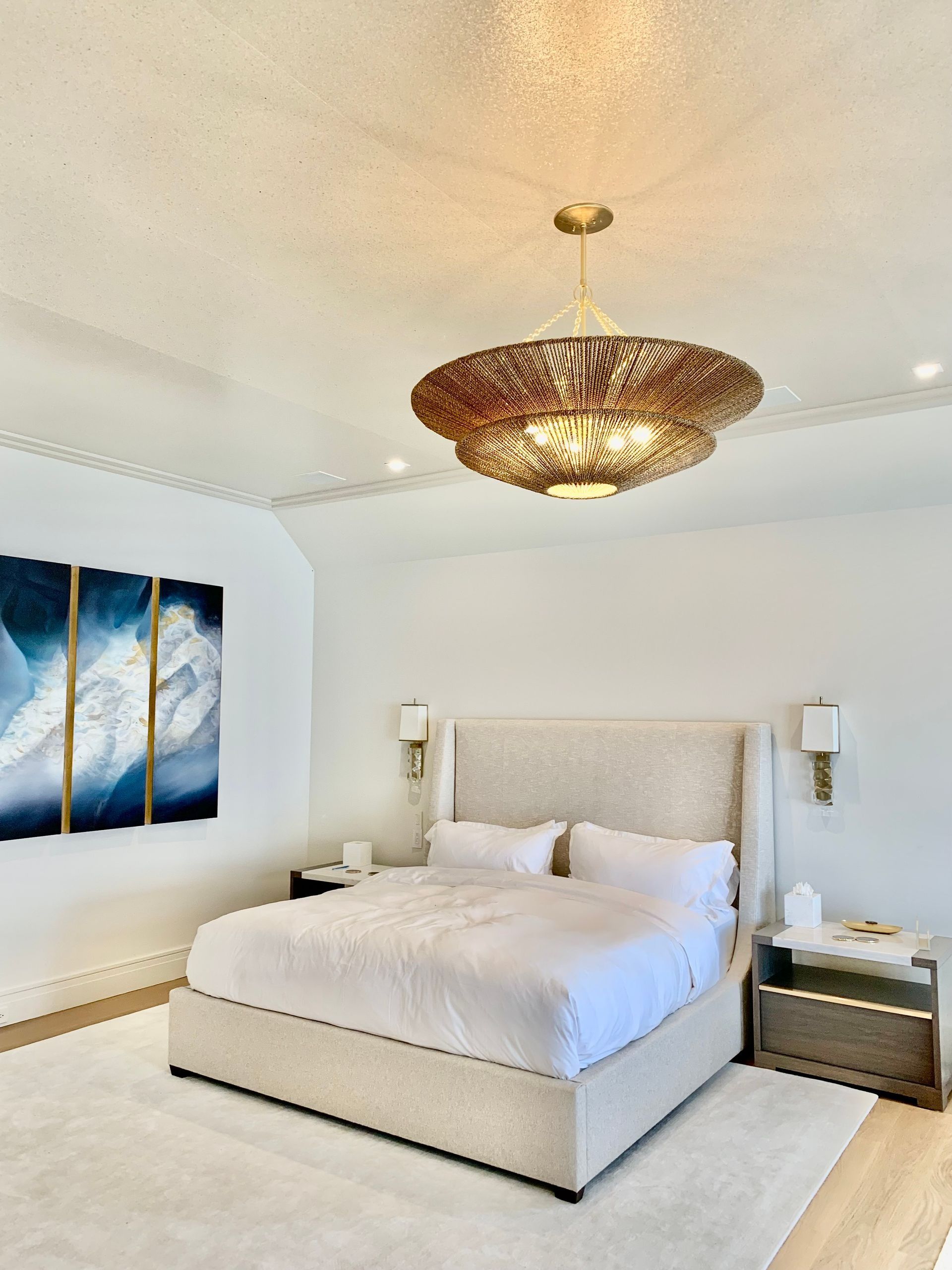 Bedroom with white walls, a bed, artwork, and a chandelier.