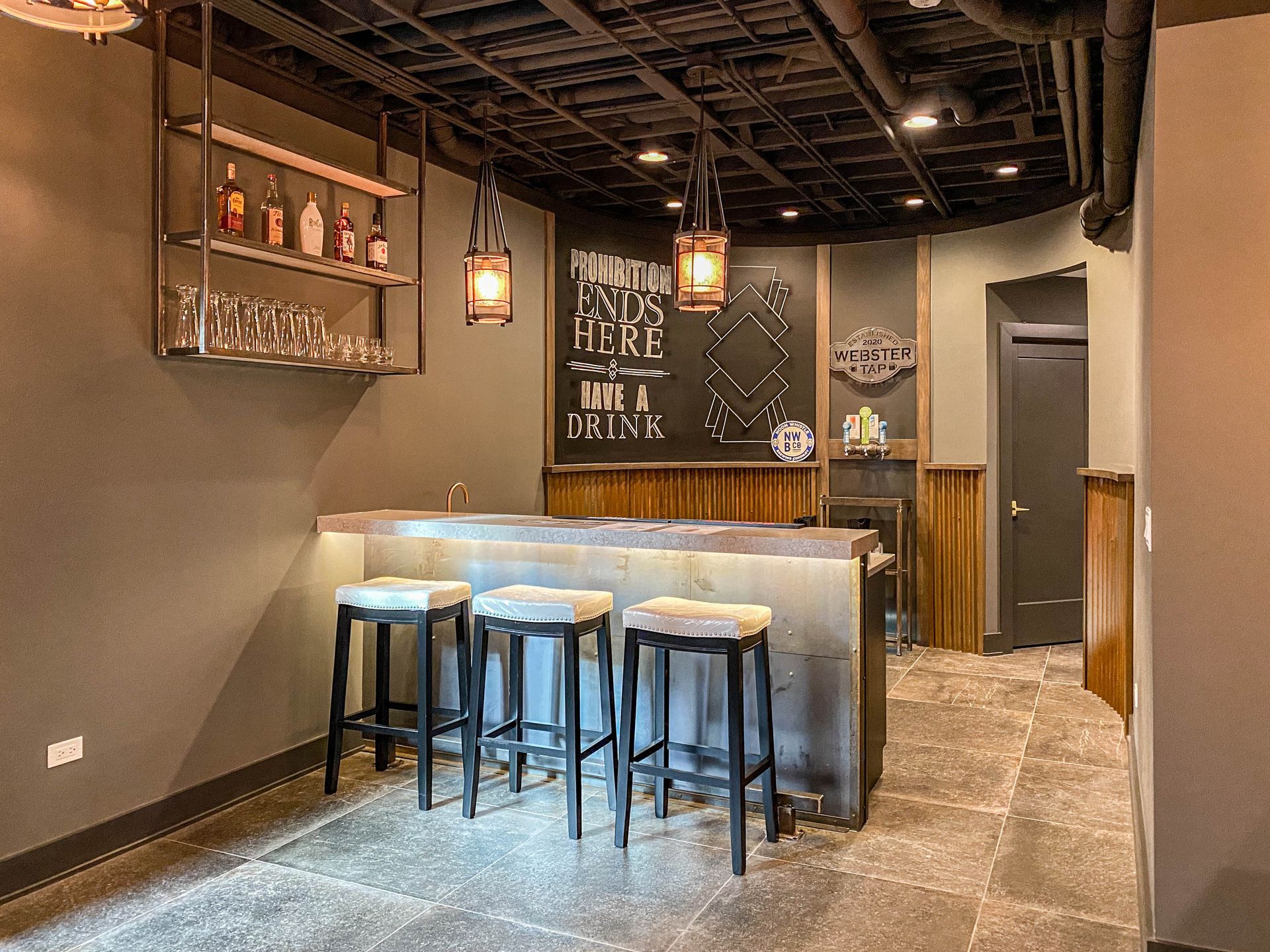 Cozy bar nook with high stools, pendant lights, chalkboard wall, and gray walls