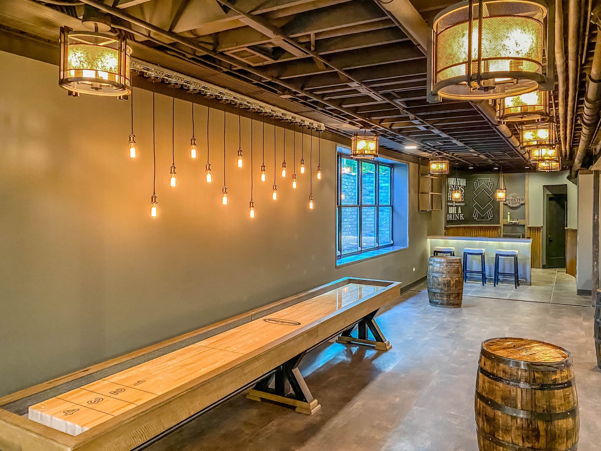Rustic indoor seating area with wooden tables, hanging lanterns, exposed ceiling, and warm ambient lighting