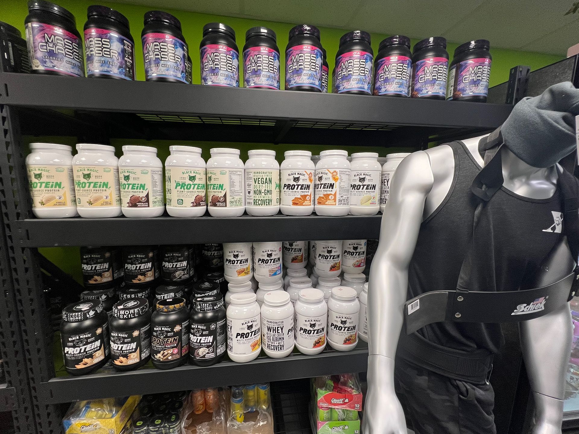 A man is standing in front of a shelf filled with bottles of supplements.