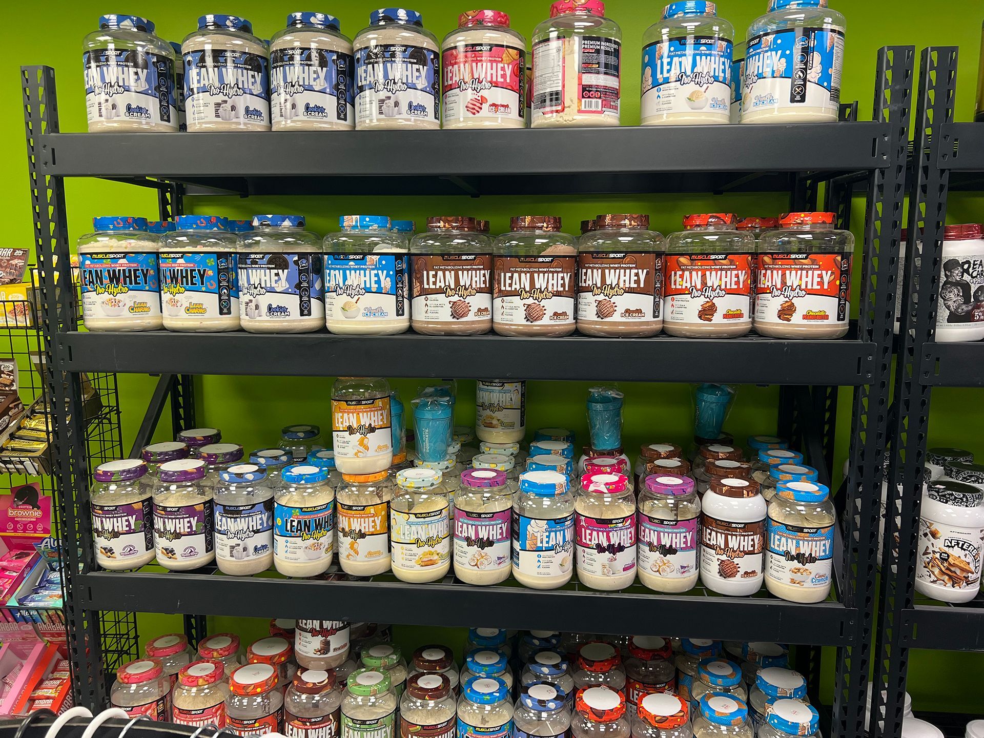 A man is standing in front of a shelf filled with bottles of supplements.