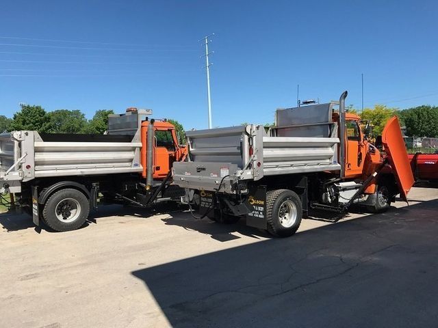 Two dump trucks are parked next to each other in a parking lot.