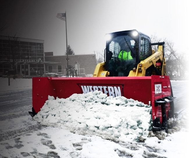 A snow plow is clearing snow from the side of the road
