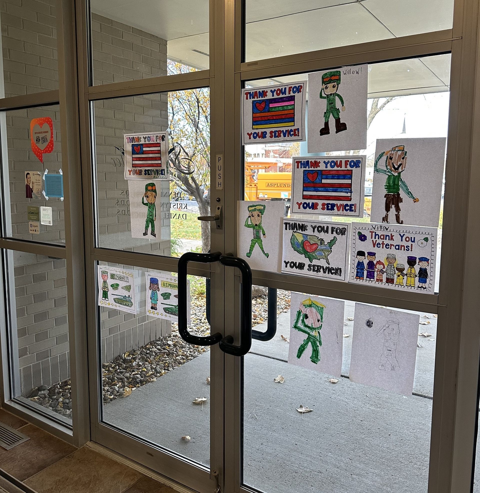 Glass doors adorned with children's drawings saying 