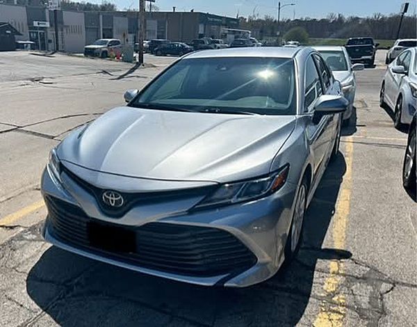 A silver toyota camry is parked in a parking lot.