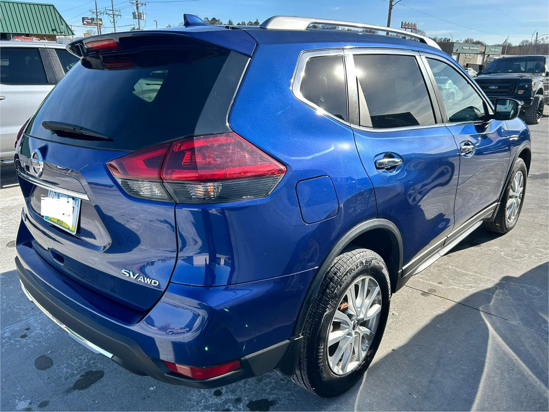 A blue nissan rogue is parked in a parking lot.