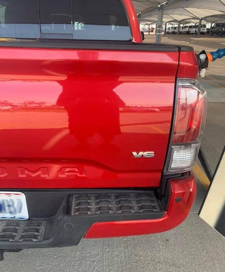 A red toyota tacoma truck is parked in a parking lot.