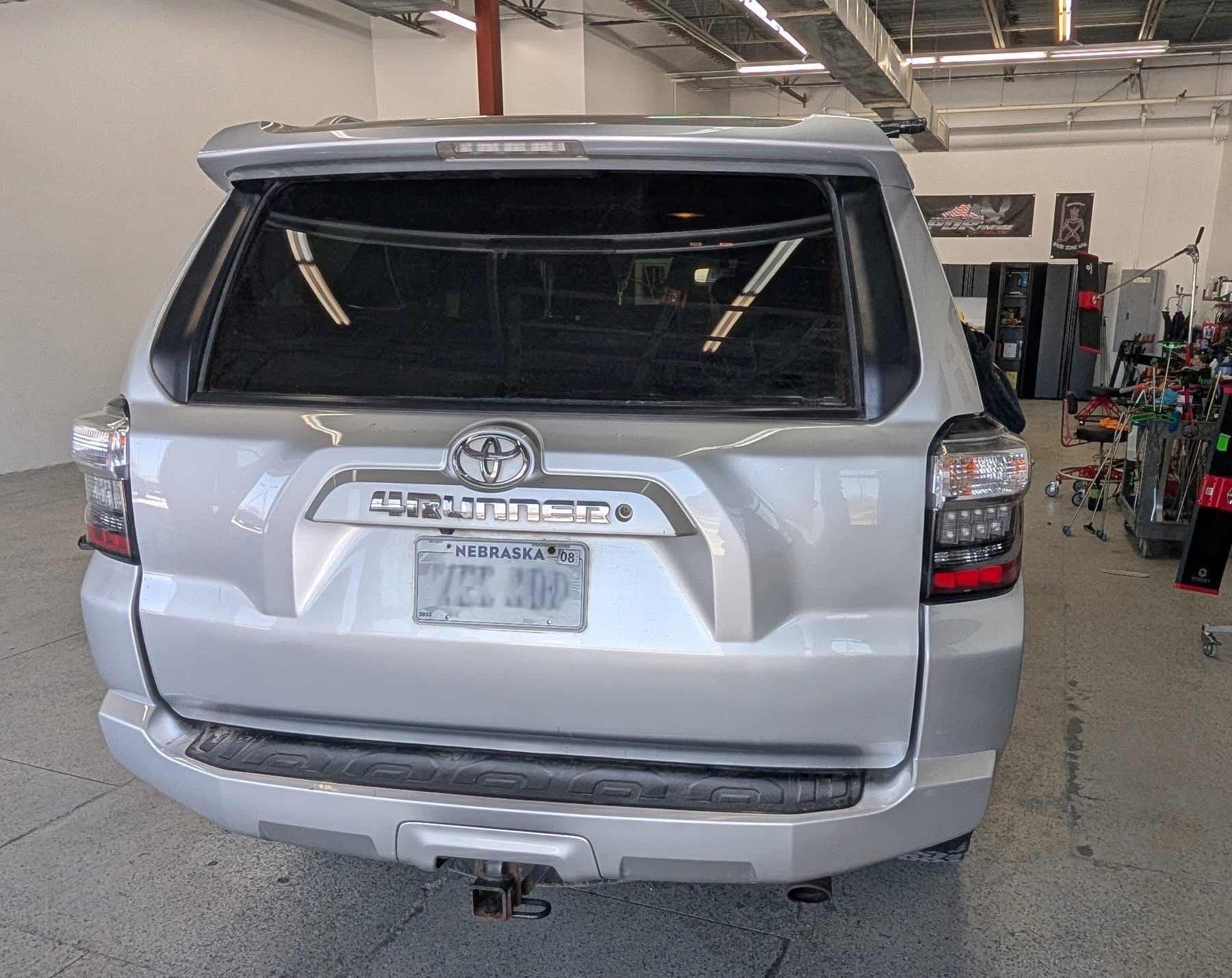 A silver toyota 4runner is parked in a garage