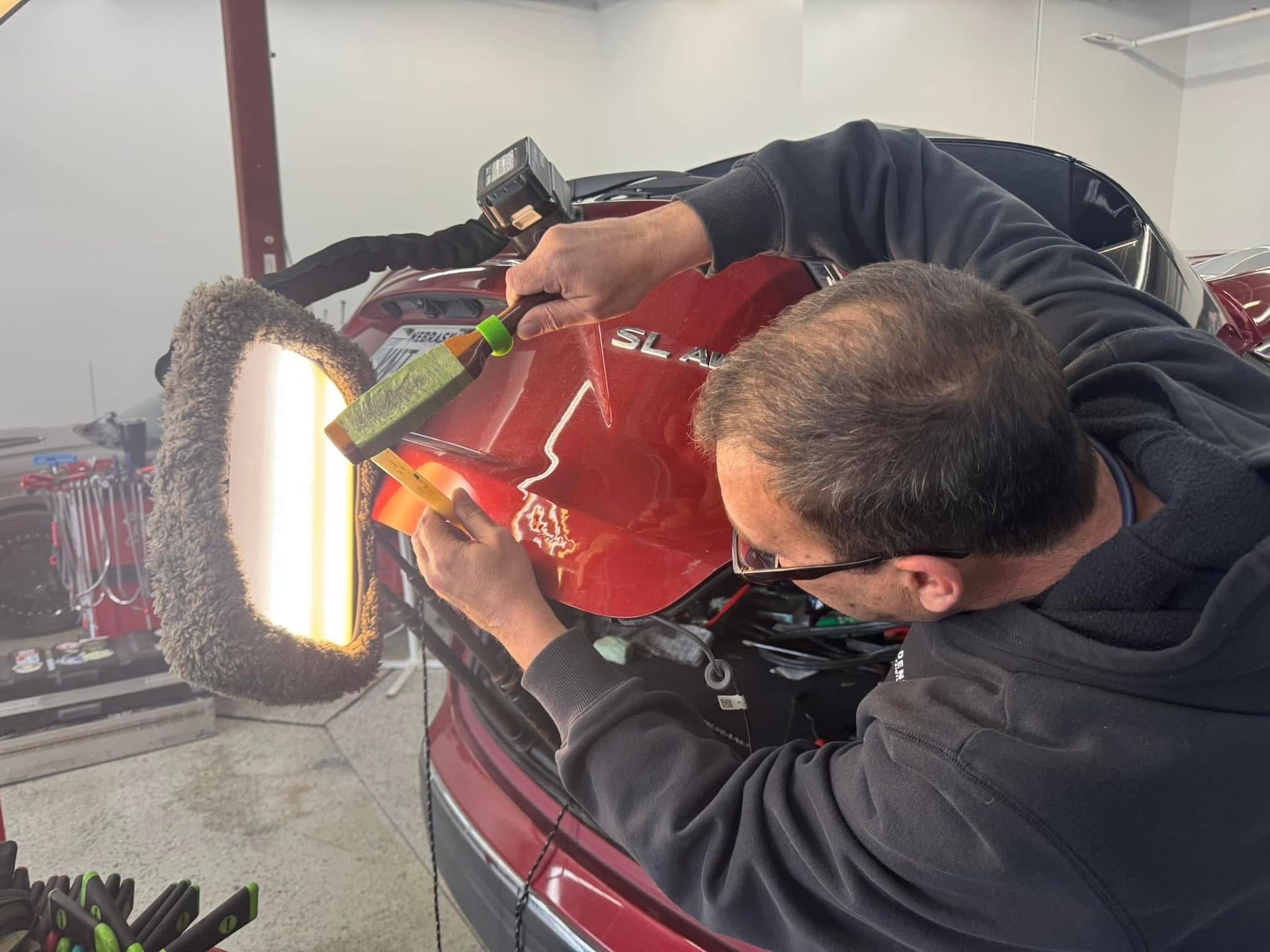 A man is working on a red car in a garage.