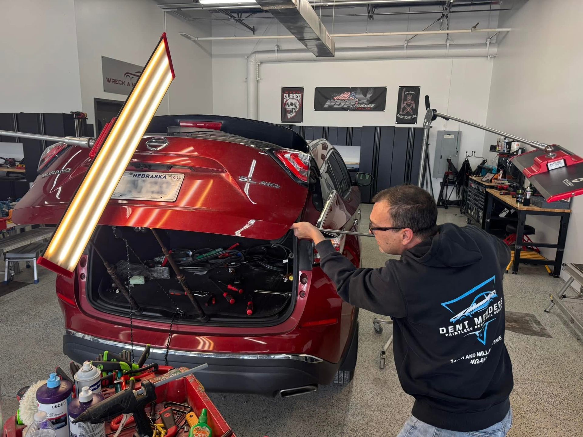 A man is working on a red car in a garage.