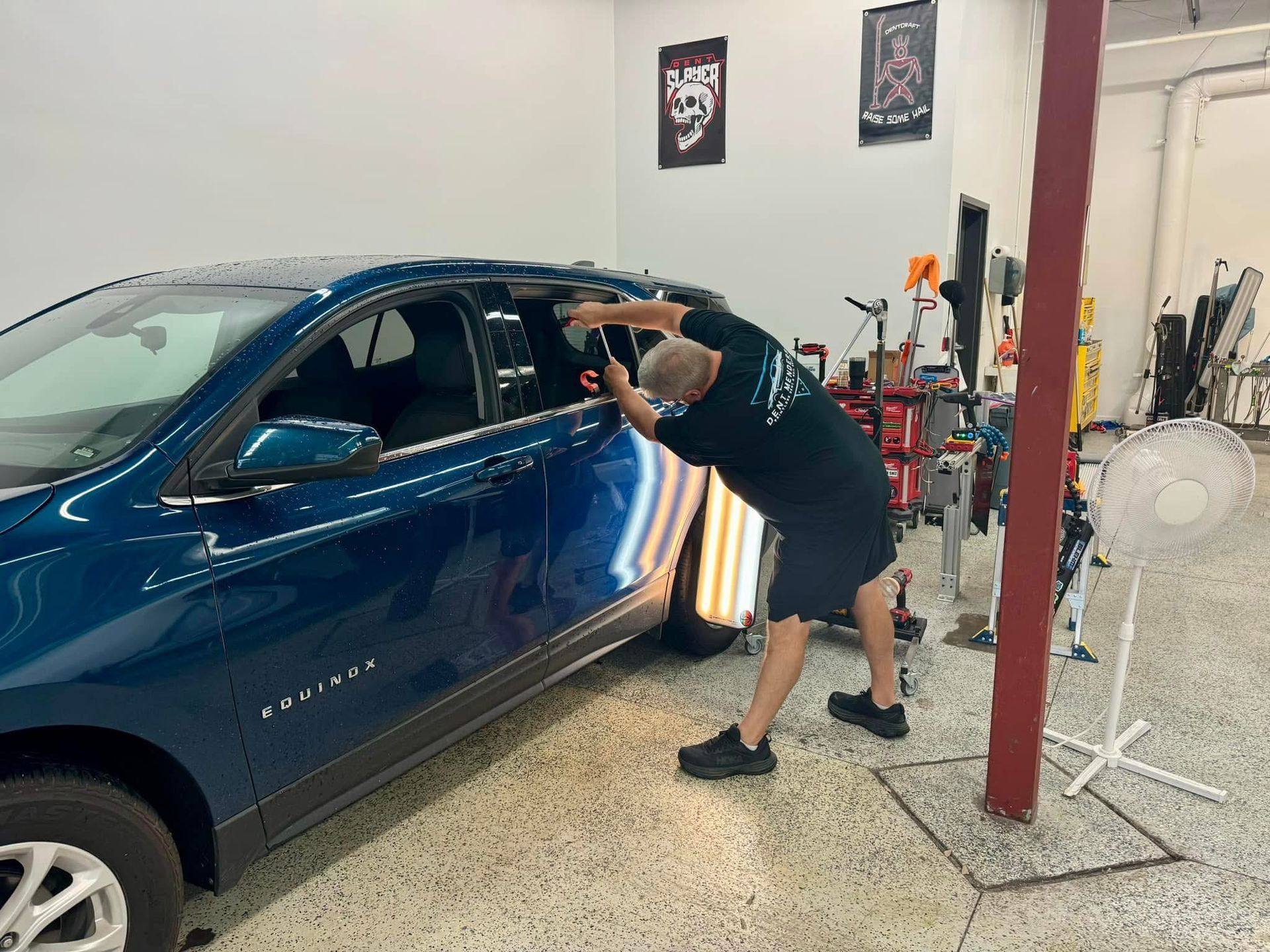 A man is working on a blue car in a garage.