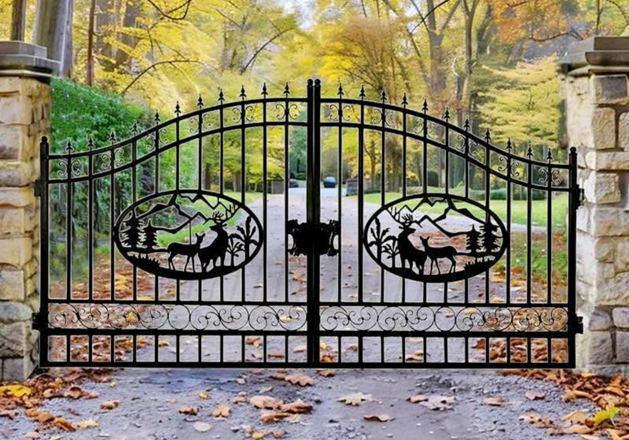 Black wrought iron driveway gate with deer and mountain silhouettes, flanked by stone columns, autumn setting.
