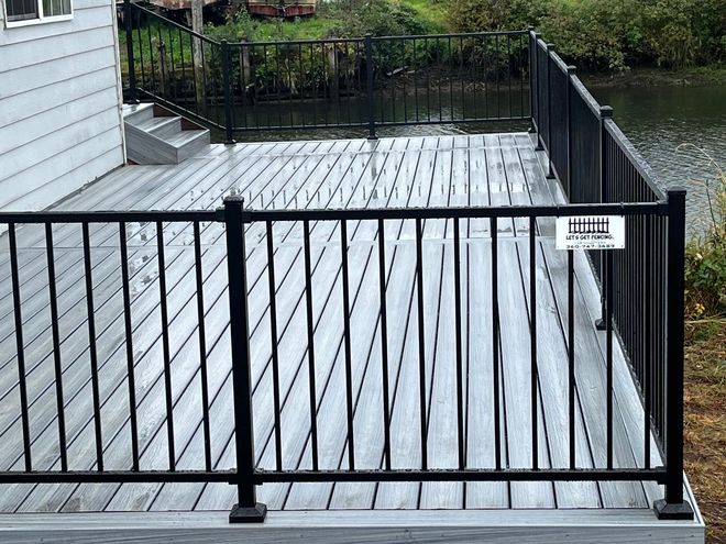 Gray deck with black railing overlooking water.